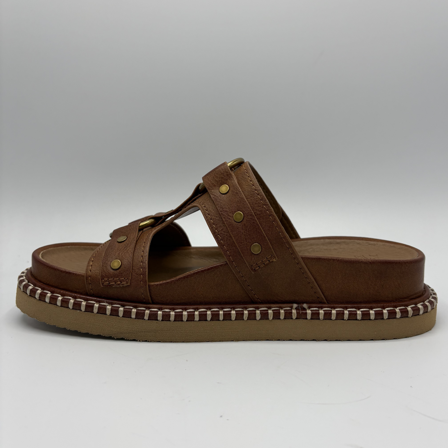 Brown sandal with a textured sole on a white background