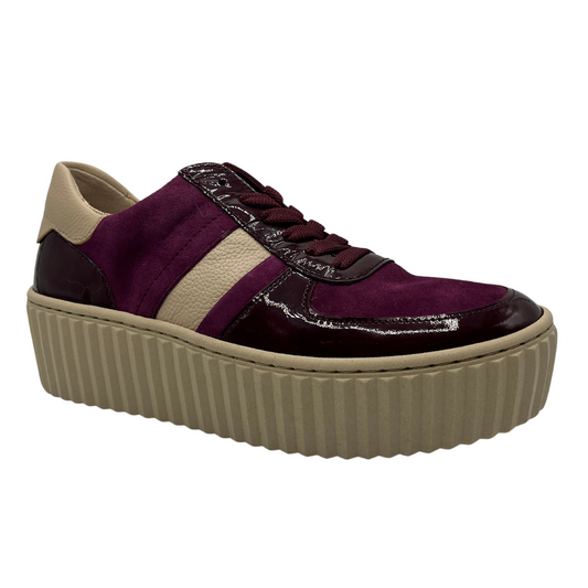 45 degree angled view of red and aubergine sneaker with cream  platform sole and lace up front.