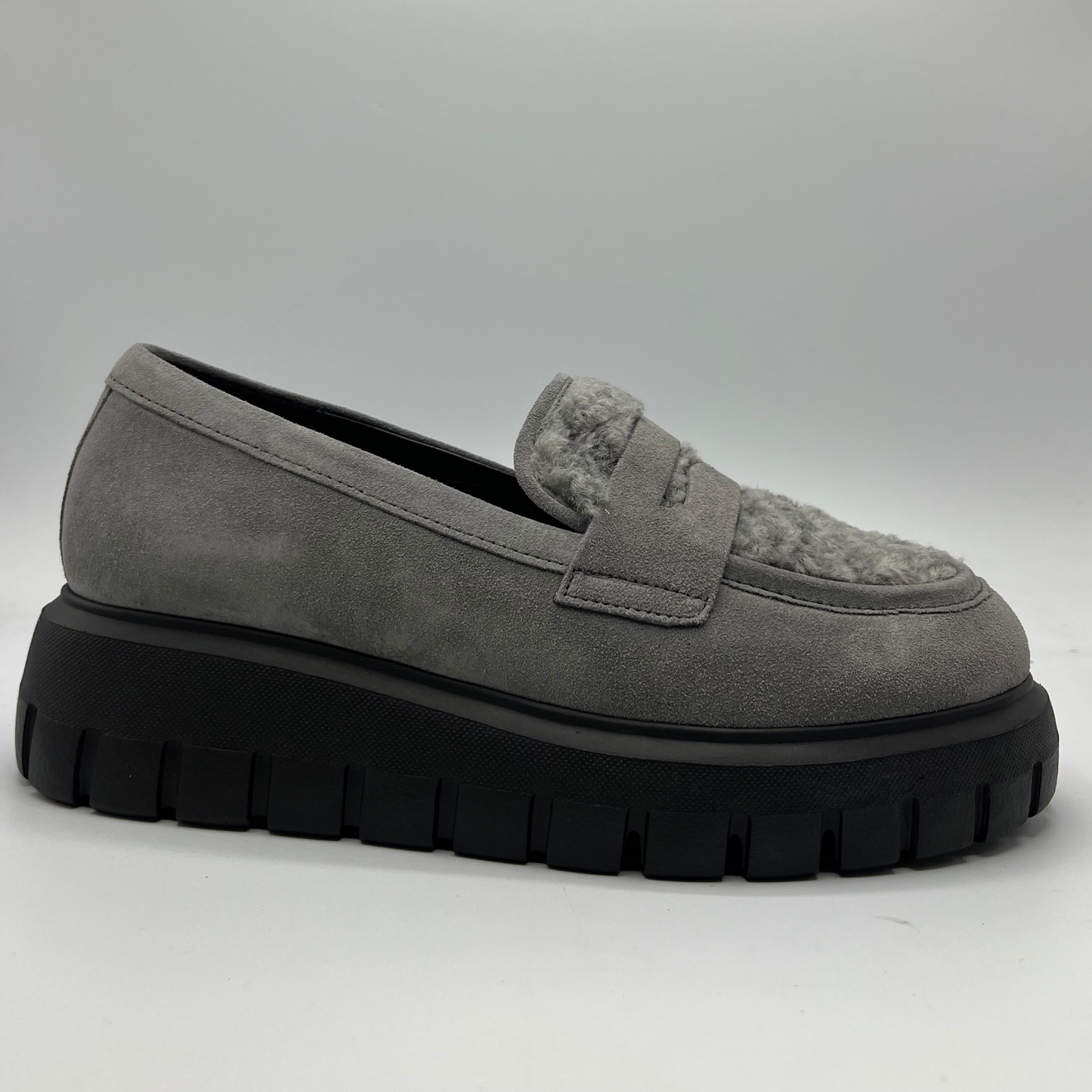 Gray suede loafer with thick black sole on a light gray background