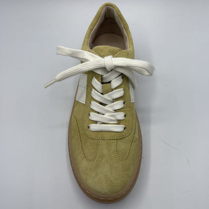 Yellow sneaker with white laces on a light gray background