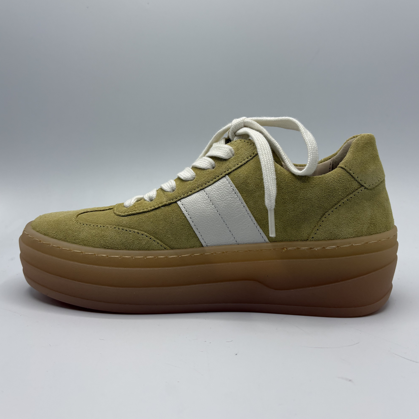 Yellow sneaker with white stripes and brown sole on a light gray background