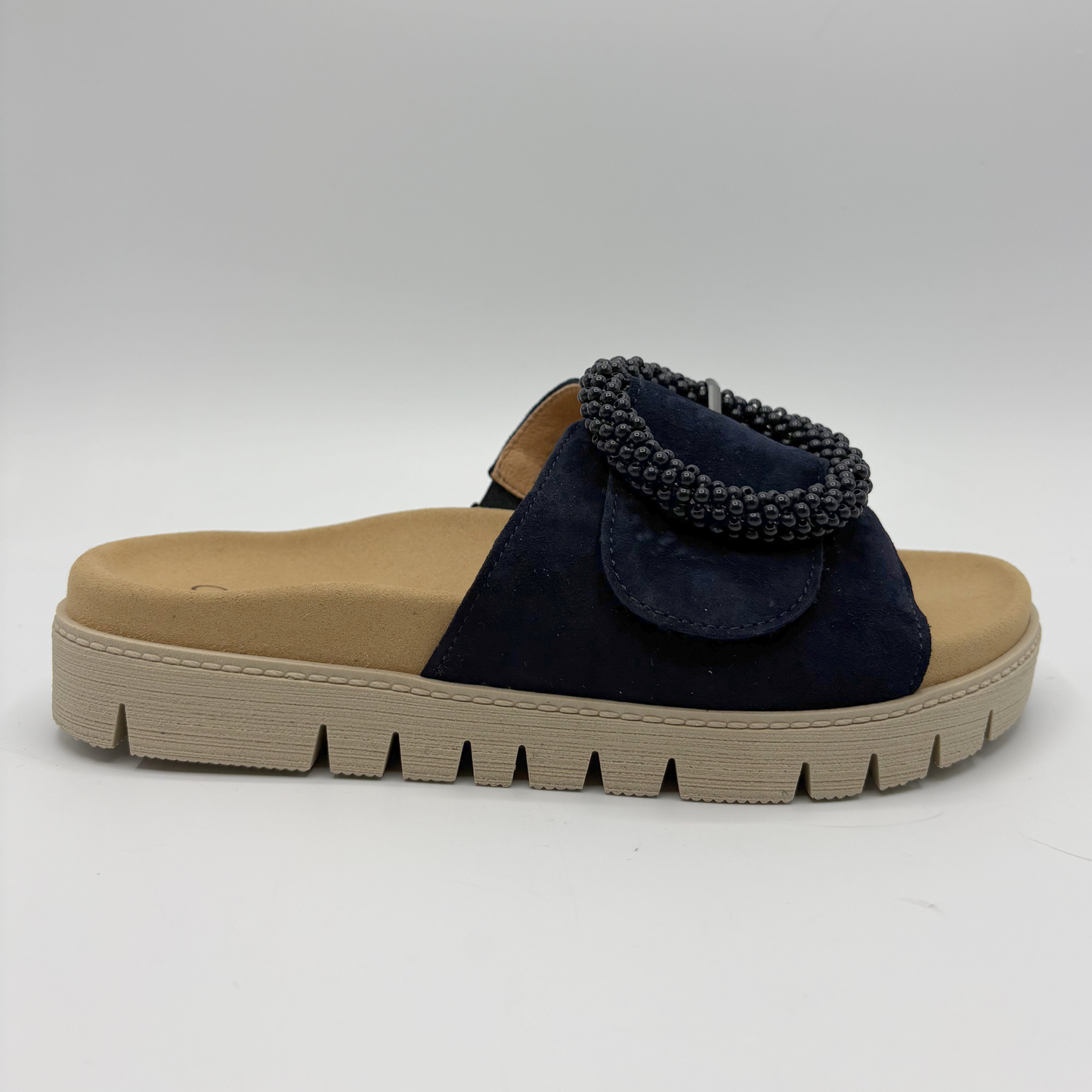 Navy sandal with decorative element on a beige sole against a white background