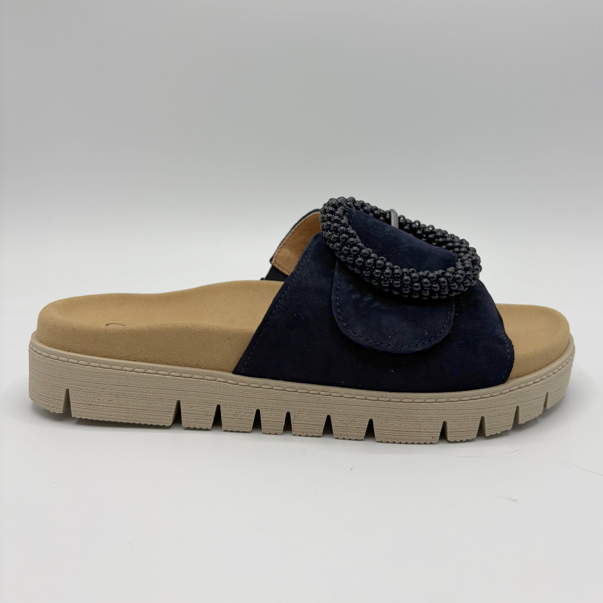 Navy sandal with decorative element on a beige sole against a white background
