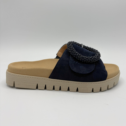 Navy sandal with decorative element on a beige sole against a white background