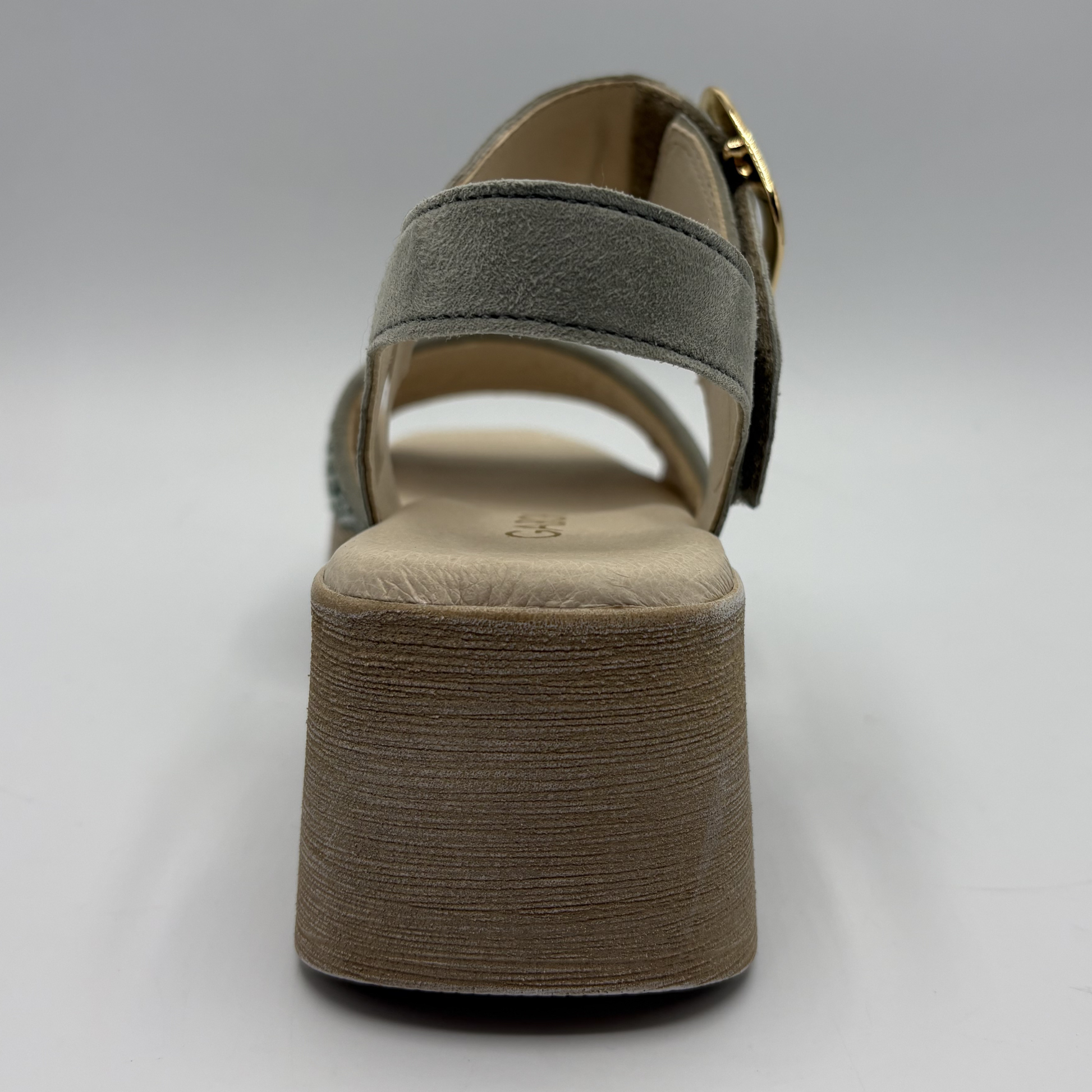 Green sandal with a textured brown sole on a light gray background