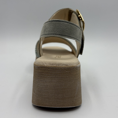 Green sandal with a textured brown sole on a light gray background