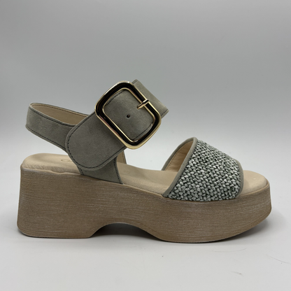 Green sandal with wooden platform and gold buckle on a gray background