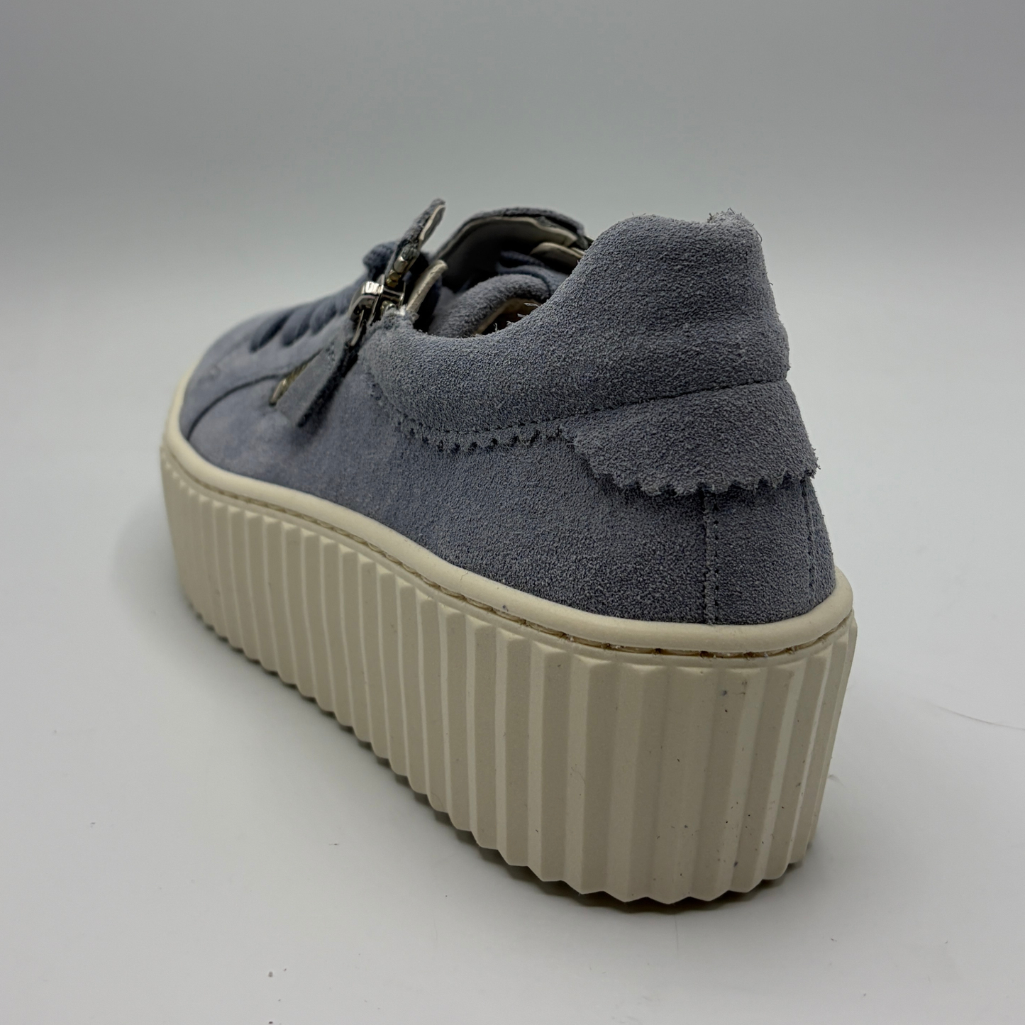 Blue suede sneaker with a thick white sole on a gray background