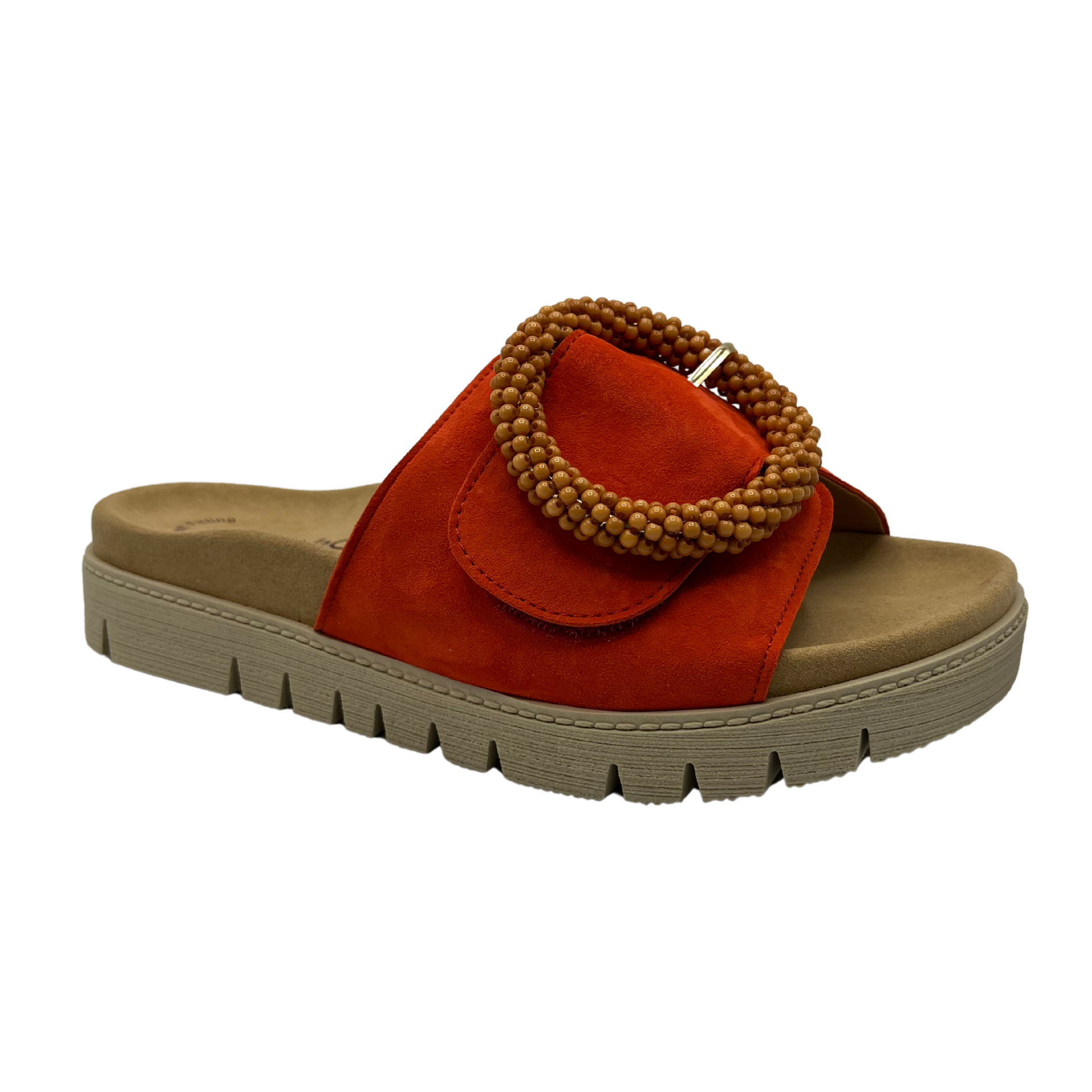45 degree angled view of orange suede slide with large buckle detail and anatomical footbed