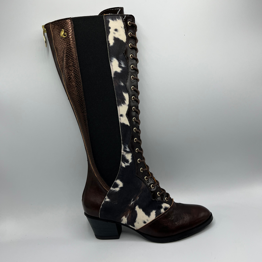 Brown knee-high boot with black and white cowhide pattern on a gray background
