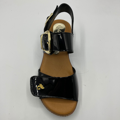 Top view of a black patent leather sandal with decorative gold buckles and a wedge heel.