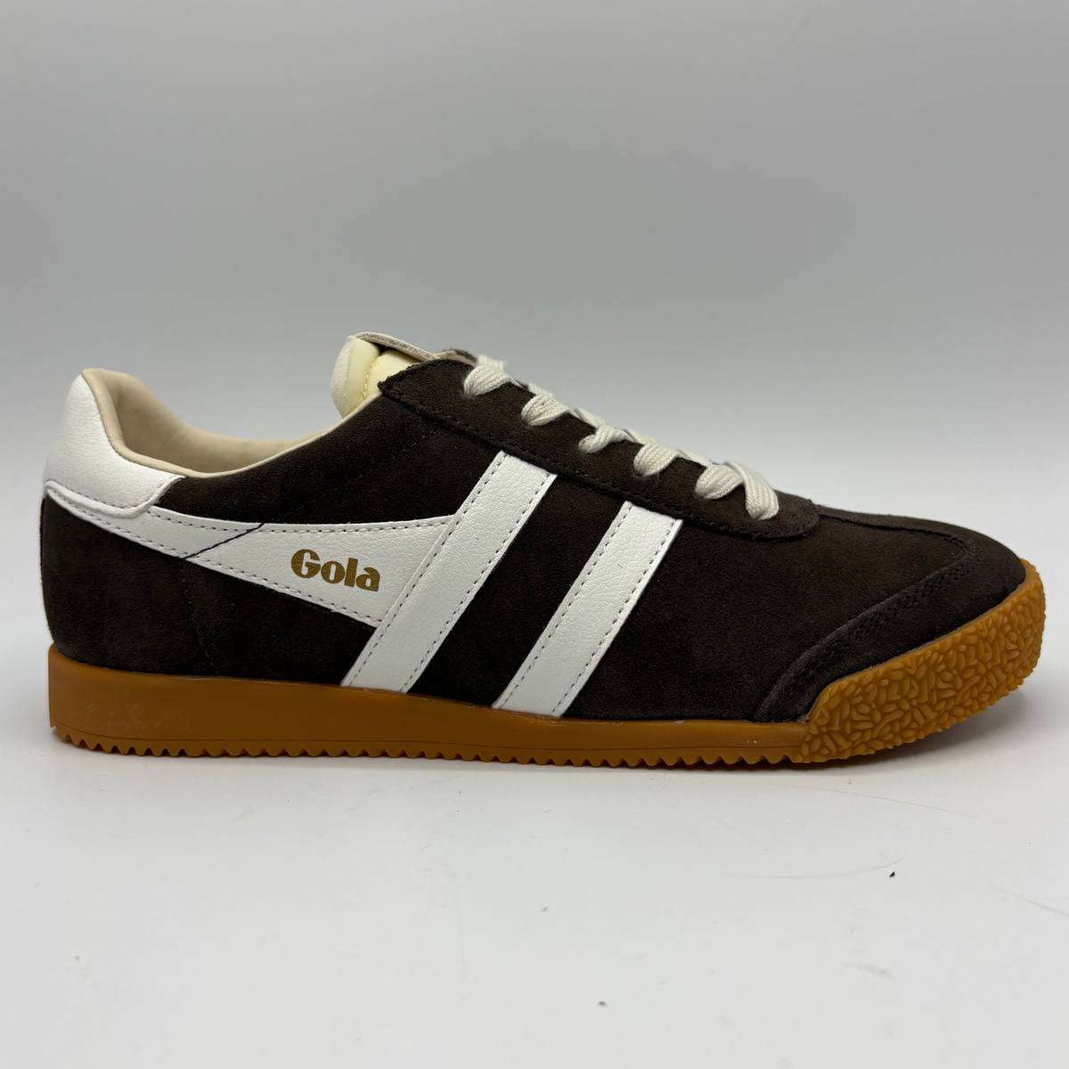 A vintage-style Samba sneaker by Gola, featuring dark brown suede and white leather panels with a gum rubber sole, shown against a neutral gray background.