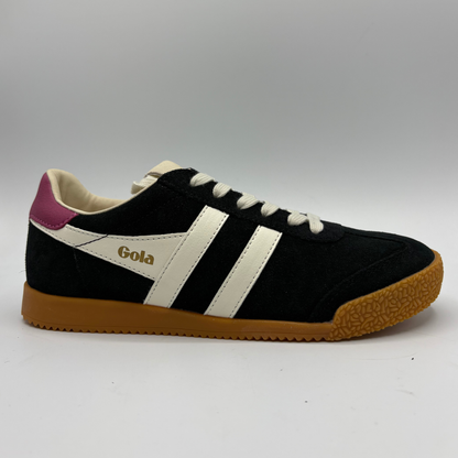 A black suede Gola sneaker with white side stripes, a magenta heel tab, and a brown gum sole, shown against a neutral gray background.