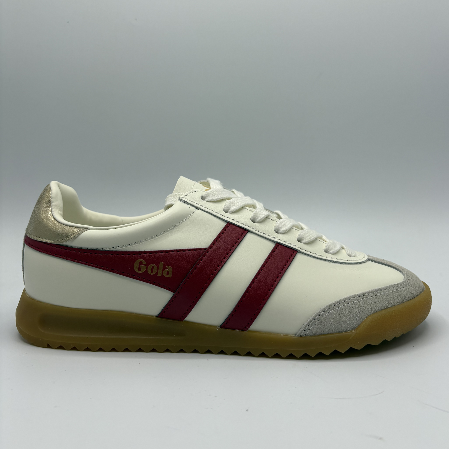White sneaker with red stripes and brown sole on a gray background
