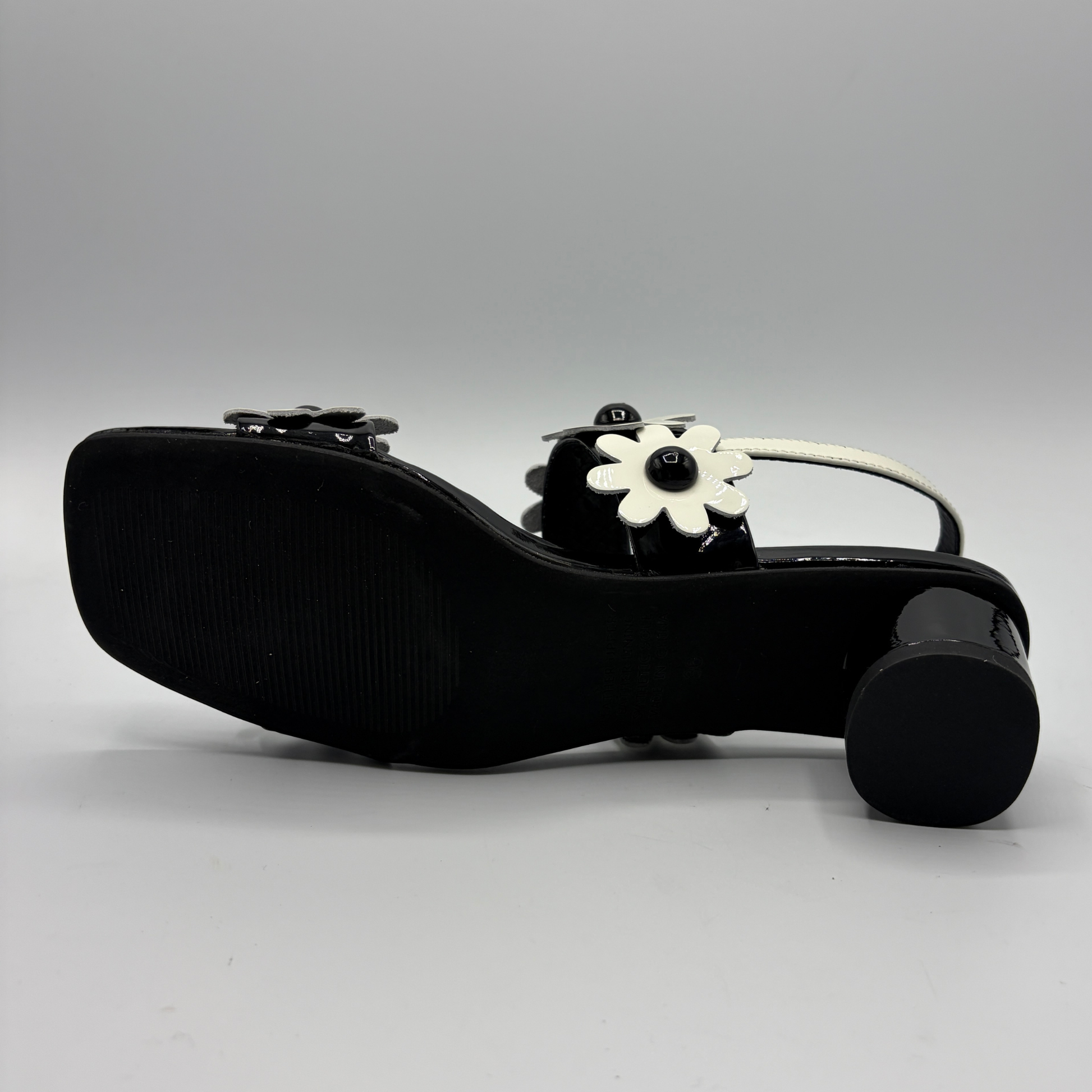 Black shoe with white flower design on a gray background