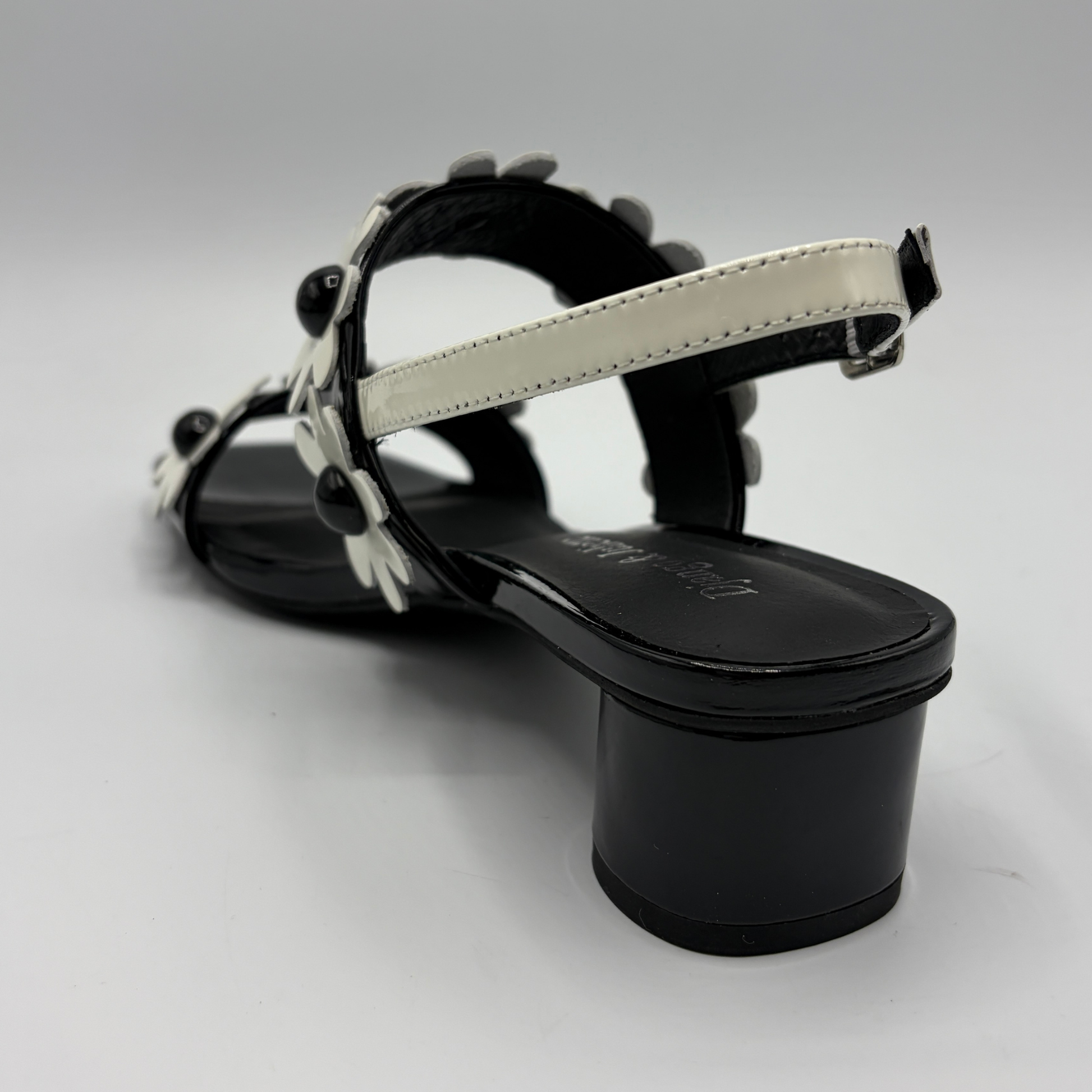Black sandal with white strap on a gray background