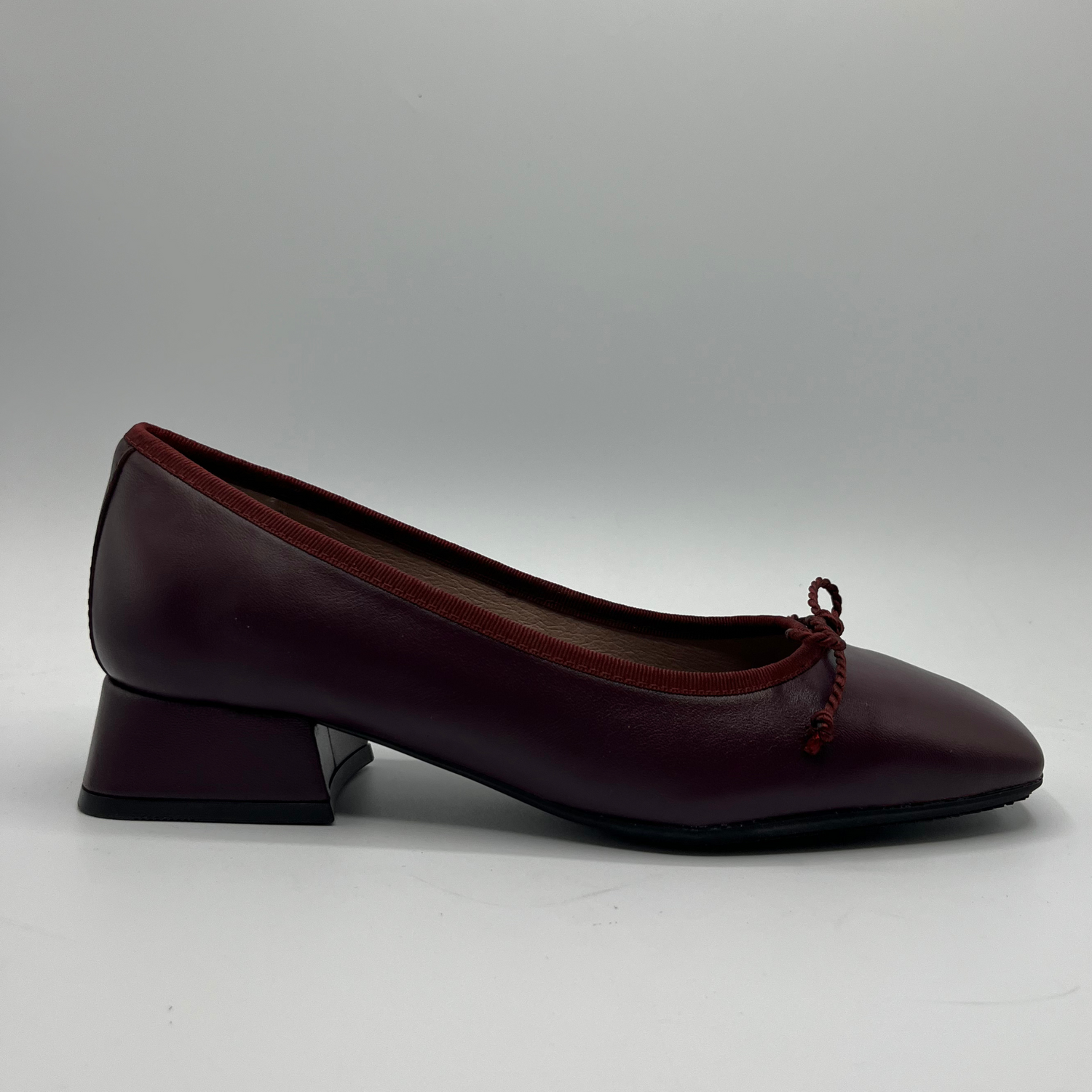 Maroon shoe with a bow on a gray background