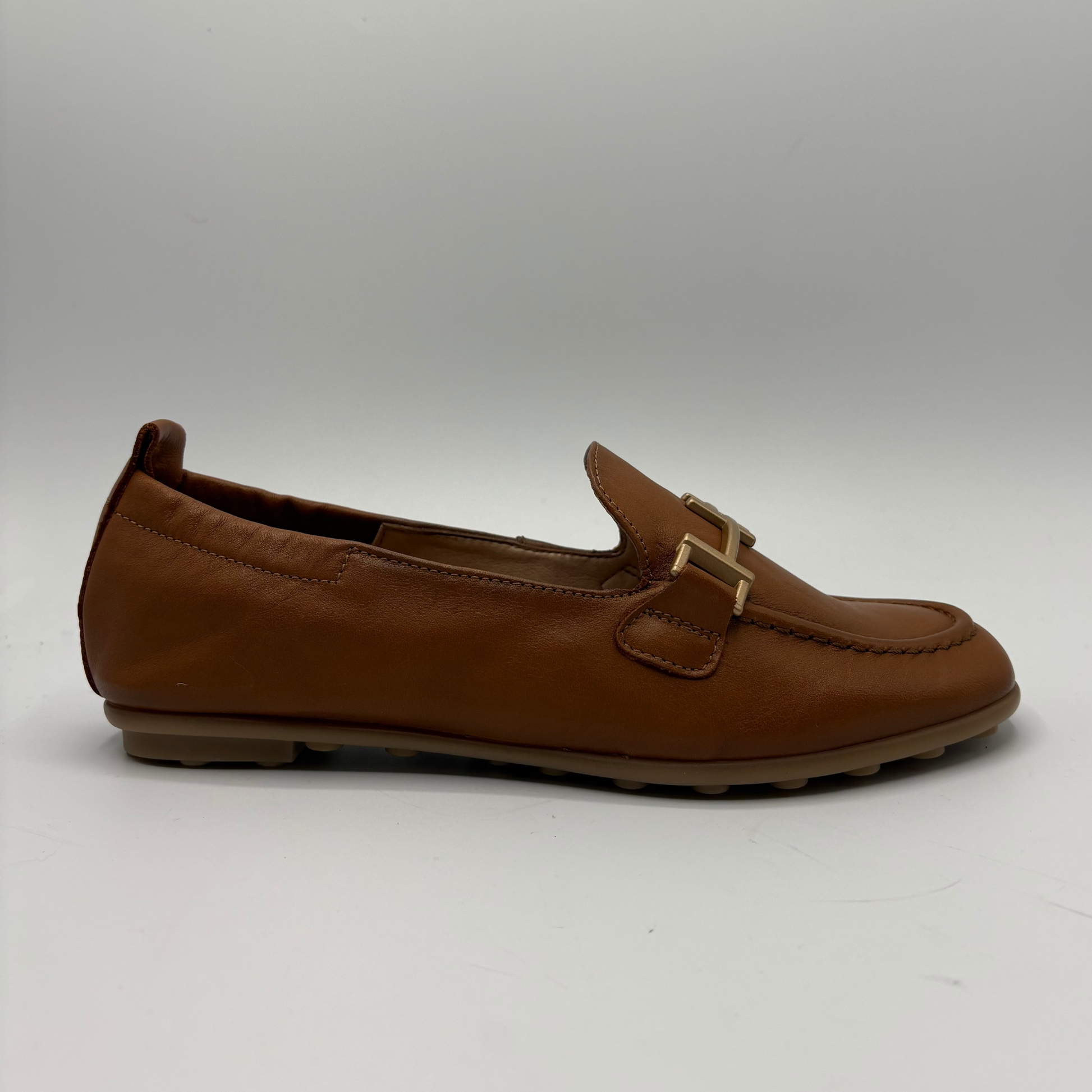 Brown leather loafer with a gold buckle on a white background