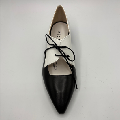 Black and white pointed-toe shoes with black laces on a light gray background