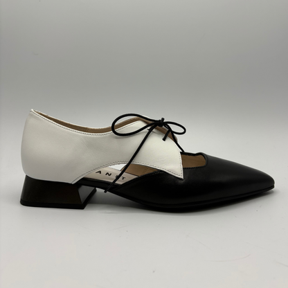 Two-tone black and white shoes with a pointed toe on a gray background