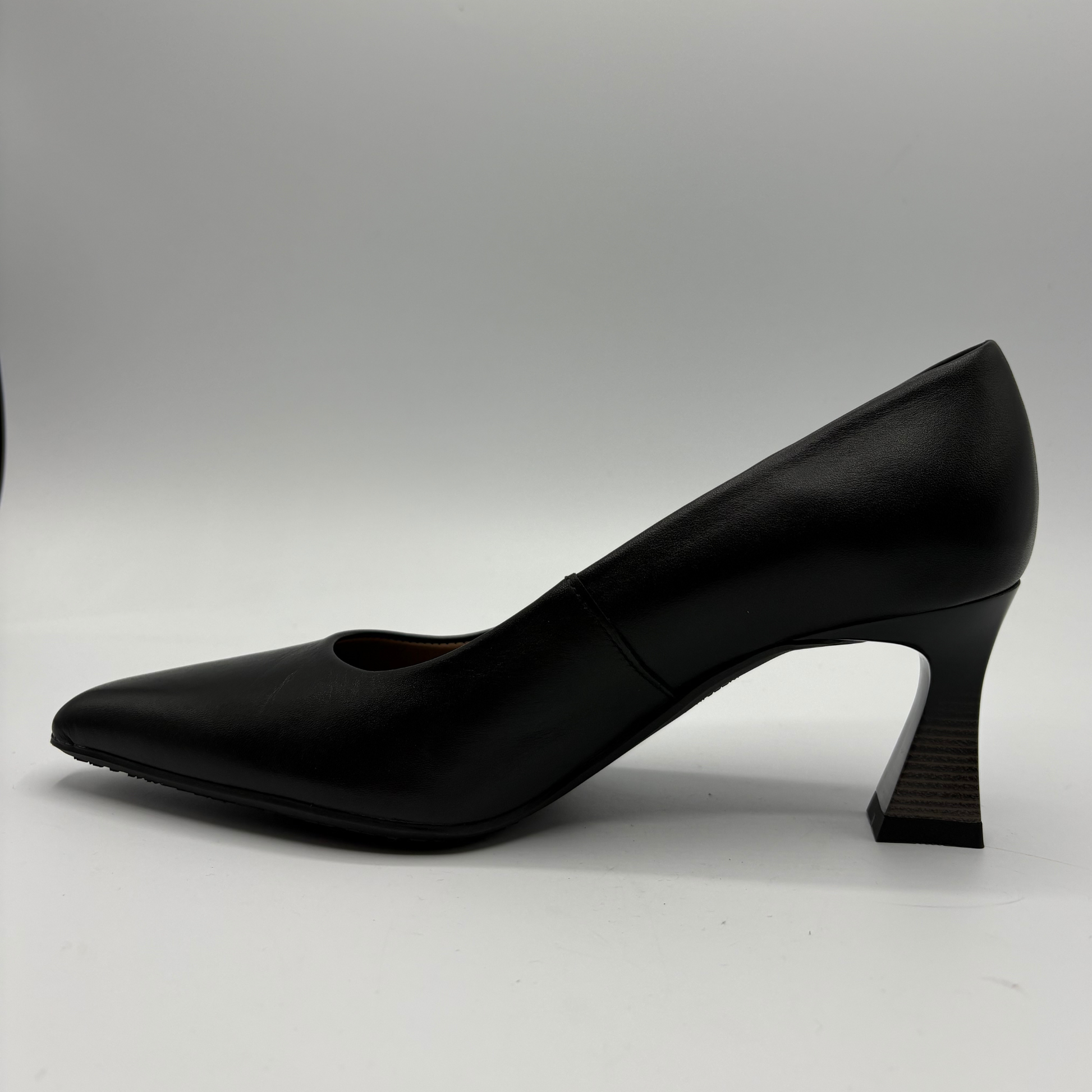 A single black leather pump with a pointed toe and a sculptural curved block heel, shown in profile against a neutral gray background.