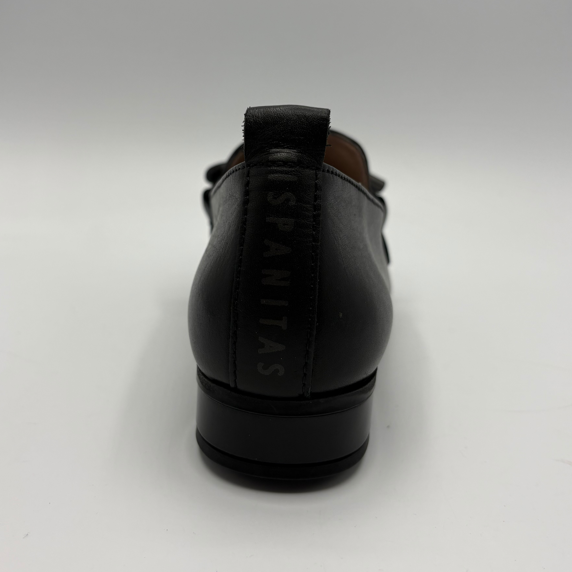 A black leather loafer shown from the back, featuring a pull tab with the brand name 'HISPANITAS' printed vertically in black.