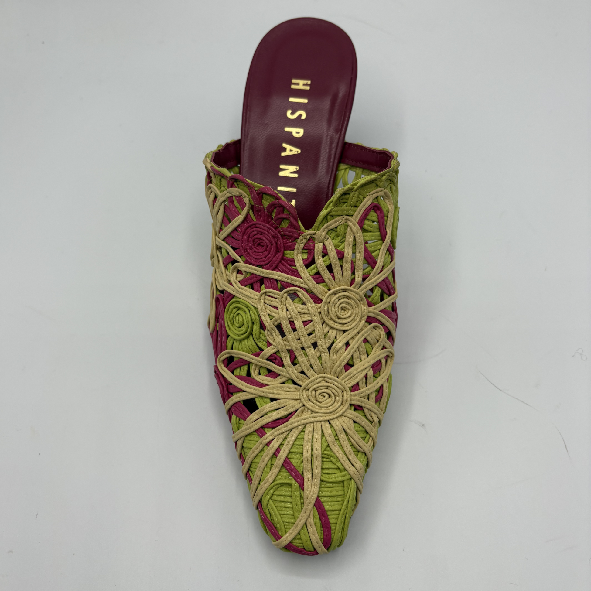 Green and pink woven shoe with 'Hispanic' branding on a gray background