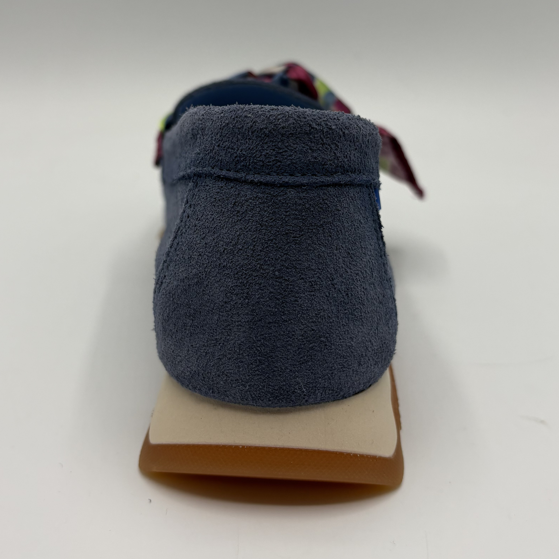 Back view of a blue suede loafer with a scarf accent
