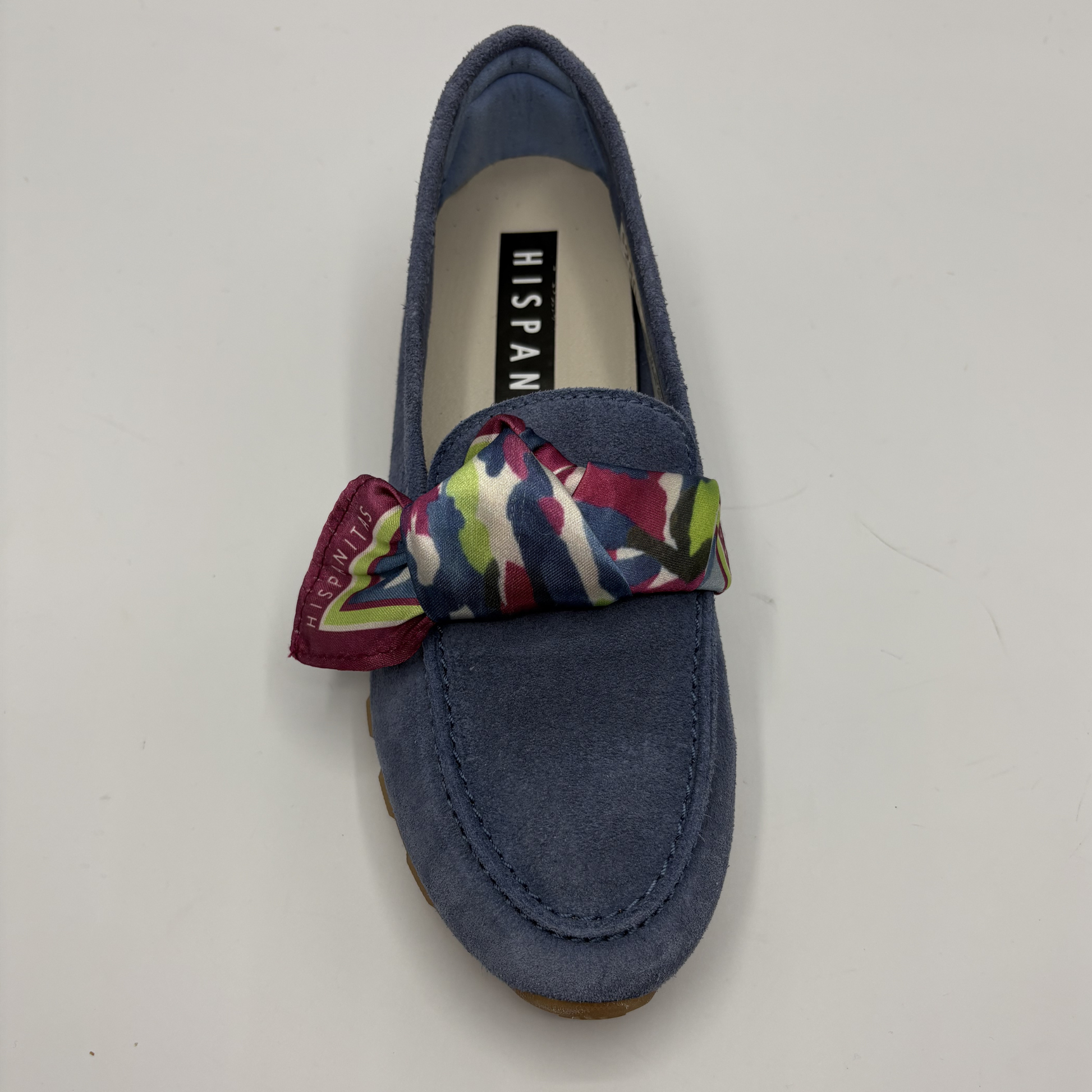 Top view of a blue suede loafer with a scarf accent