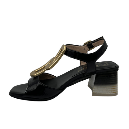 Left facing view of black patent leather sandal with ombre heel and gold brooch detail on upper