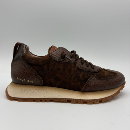 A brown leather sneaker with a textured patterned side panel, a beige midsole embossed with 'HISPANITAS', and a brown lug sole, shown against a neutral gray background.