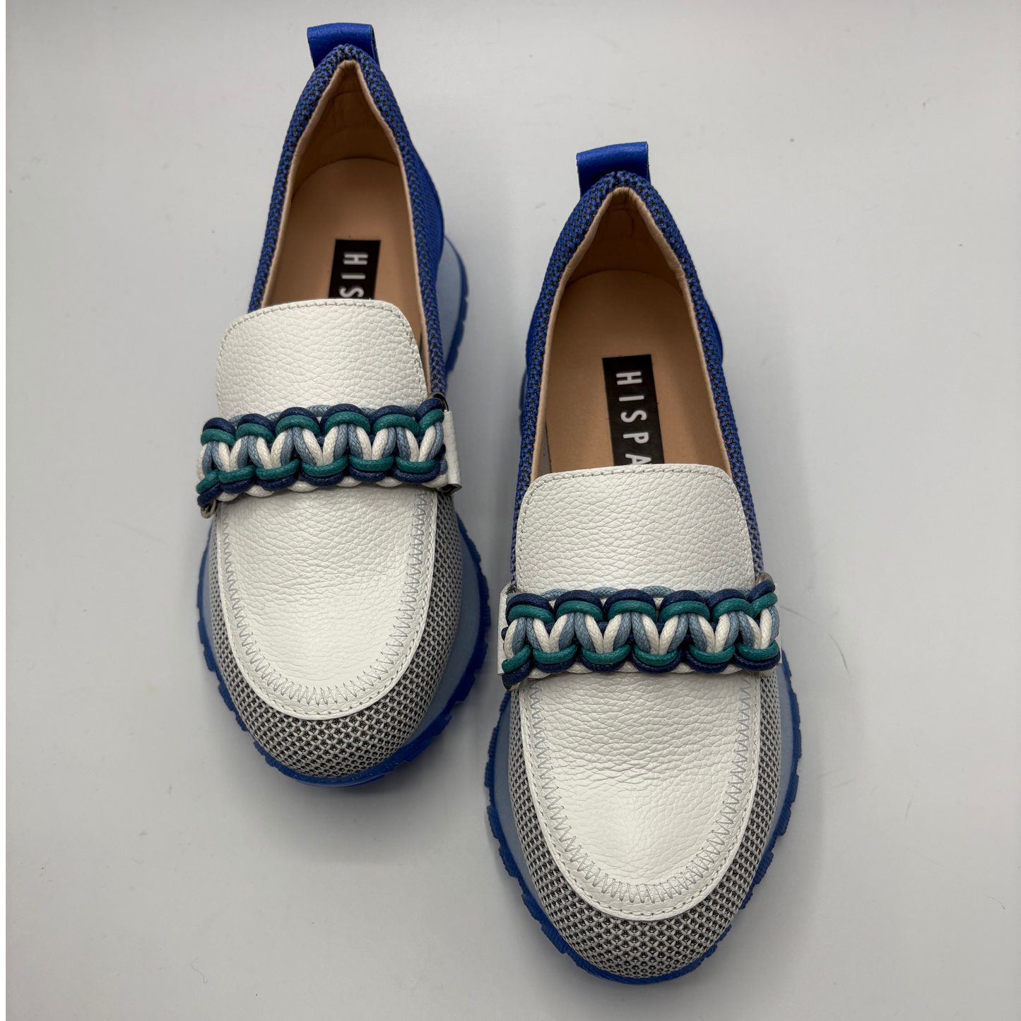 White loafers with blue and green accents on a light gray background