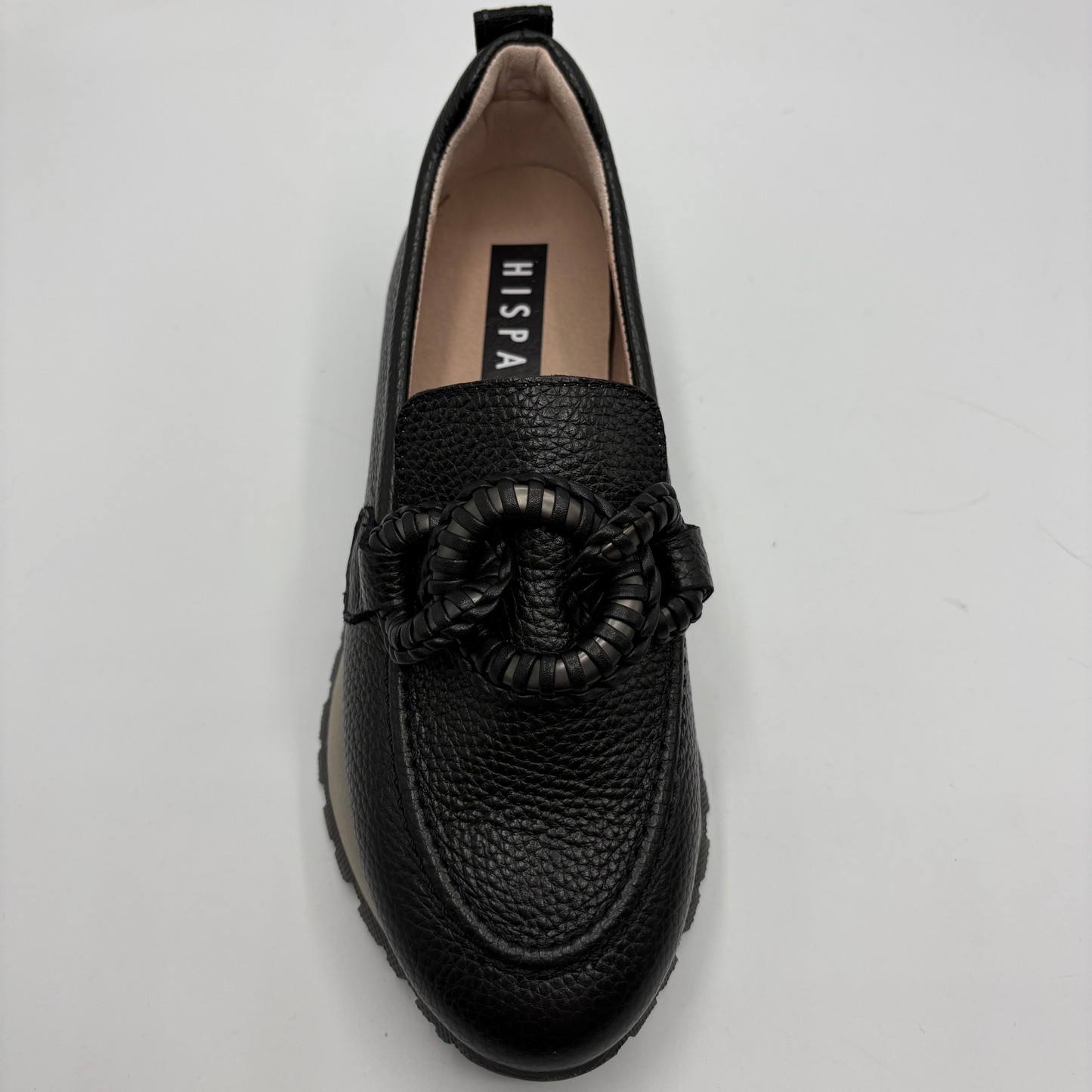 A black pebbled leather slip-on loafer with a braided rope detail across the vamp, photographed from a top-down angle on a light gray background. The insole features the brand name 'HISPANITAS’