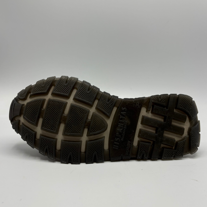 The treaded outsole of a black and dark brown shoe, showing the ‘HISPANITAS' brand name molded into the rubber, photographed on a light gray background.
