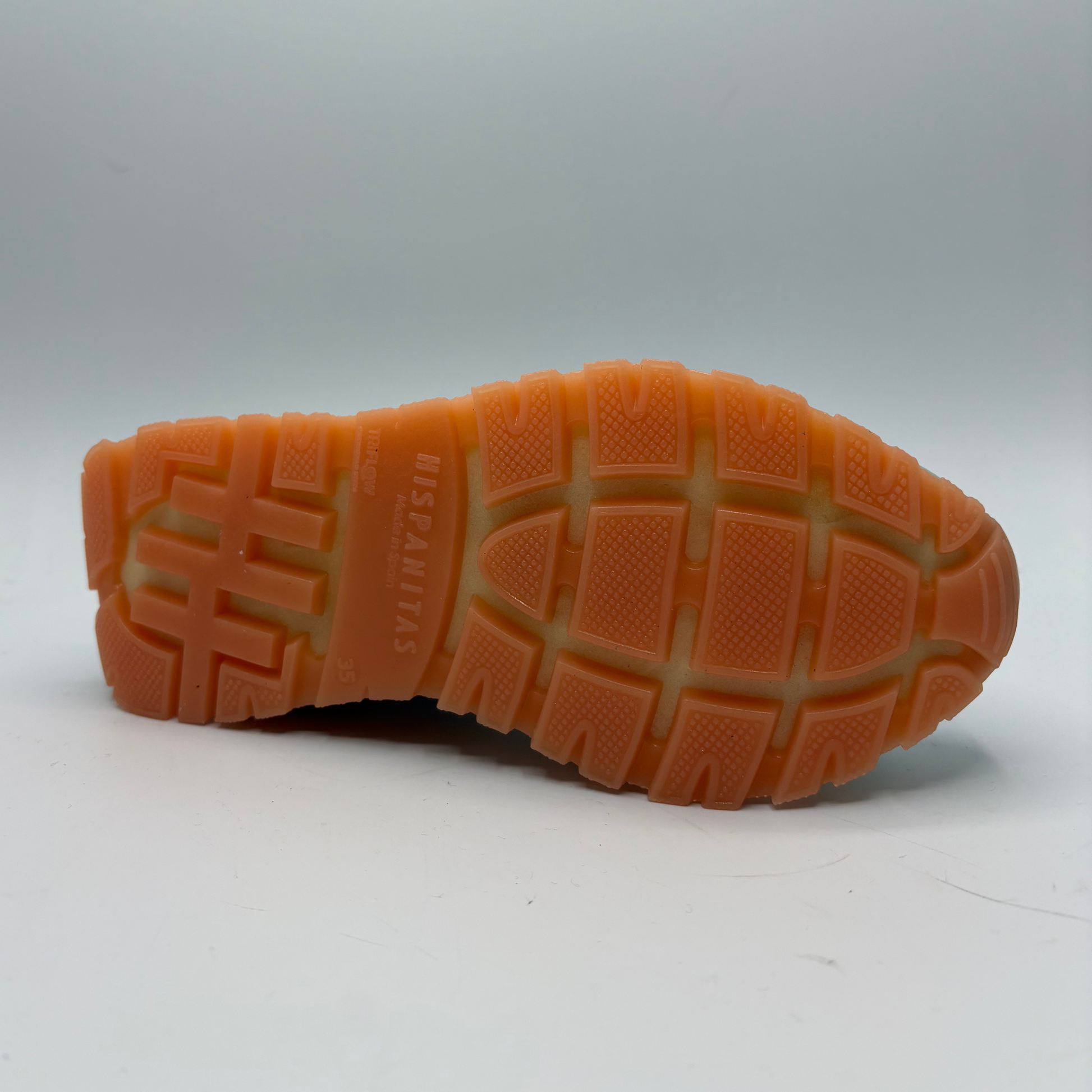 Close-up of an orange sole with tread pattern on a white background