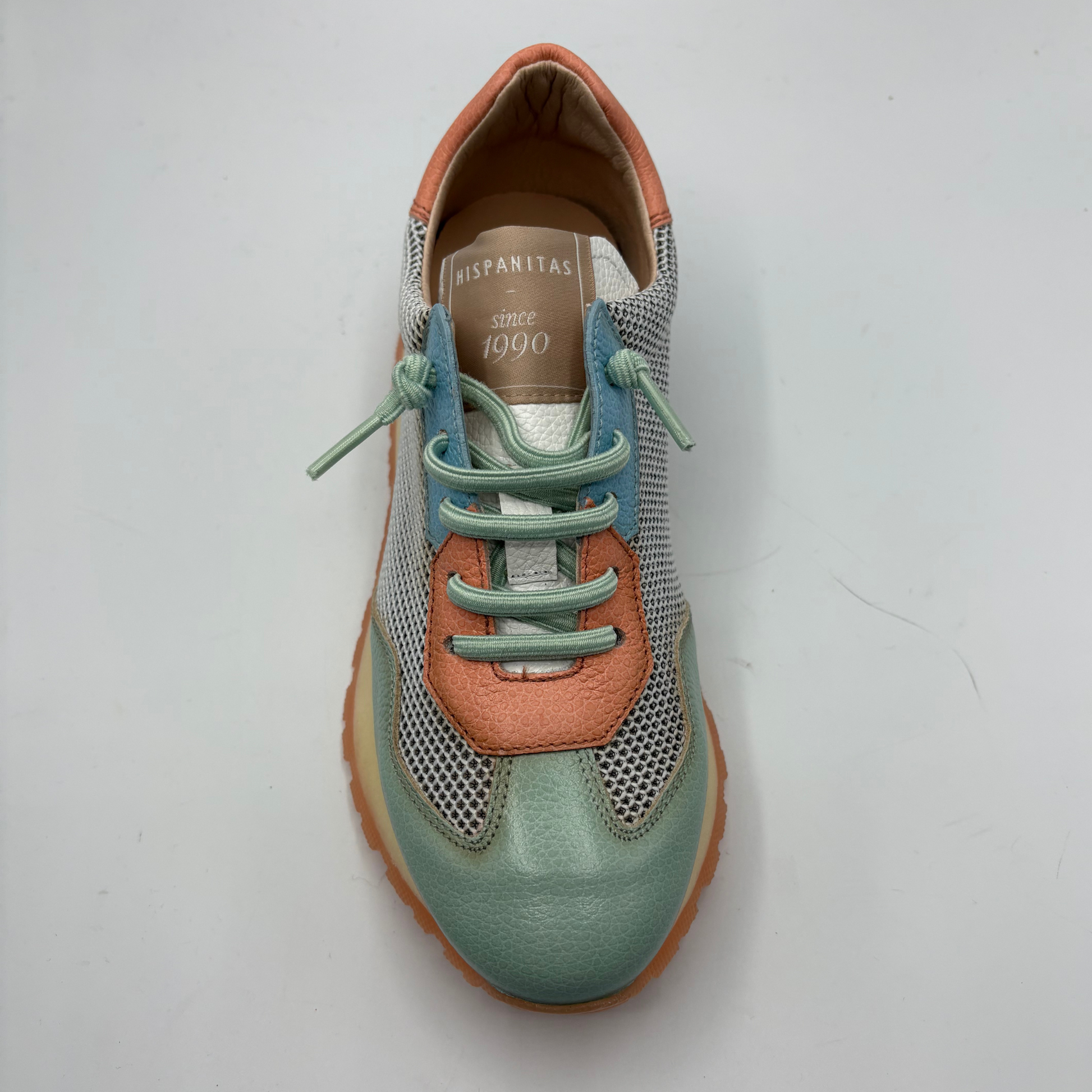 Green and orange sneaker with blue laces on a white background