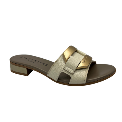 Angled view of slip on sandal with a cream coloured leather strap. Leather lined, short block heel and gold detail on upper.
