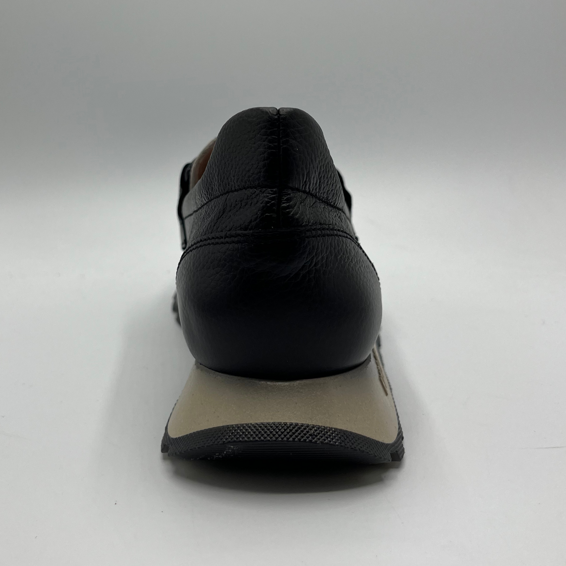 Black shoe with a beige sole on a white background