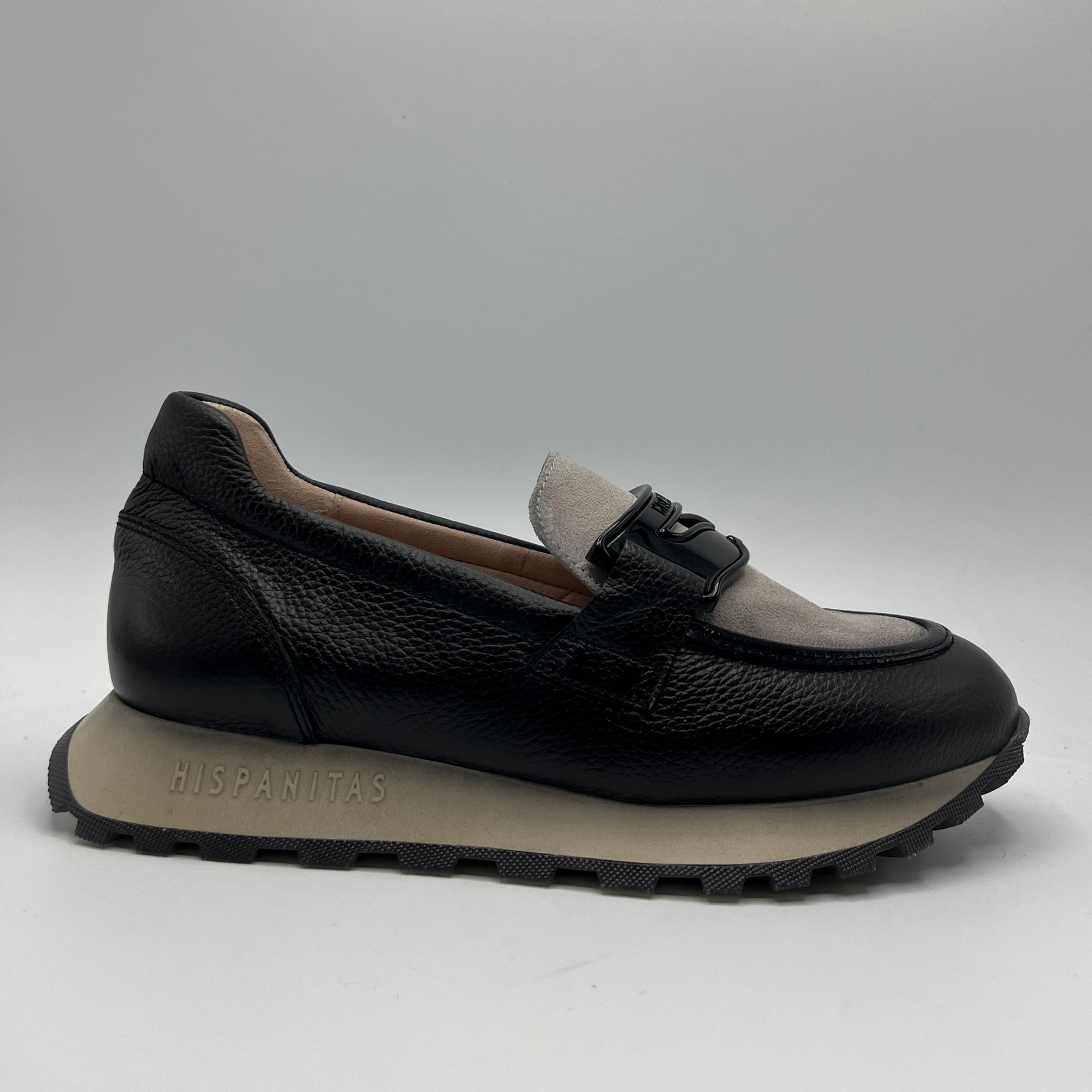 Black loafer shoe with beige lining on a gray background
