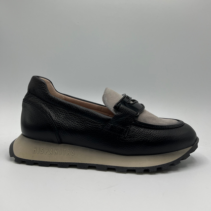 Black loafer shoe with beige lining on a gray background