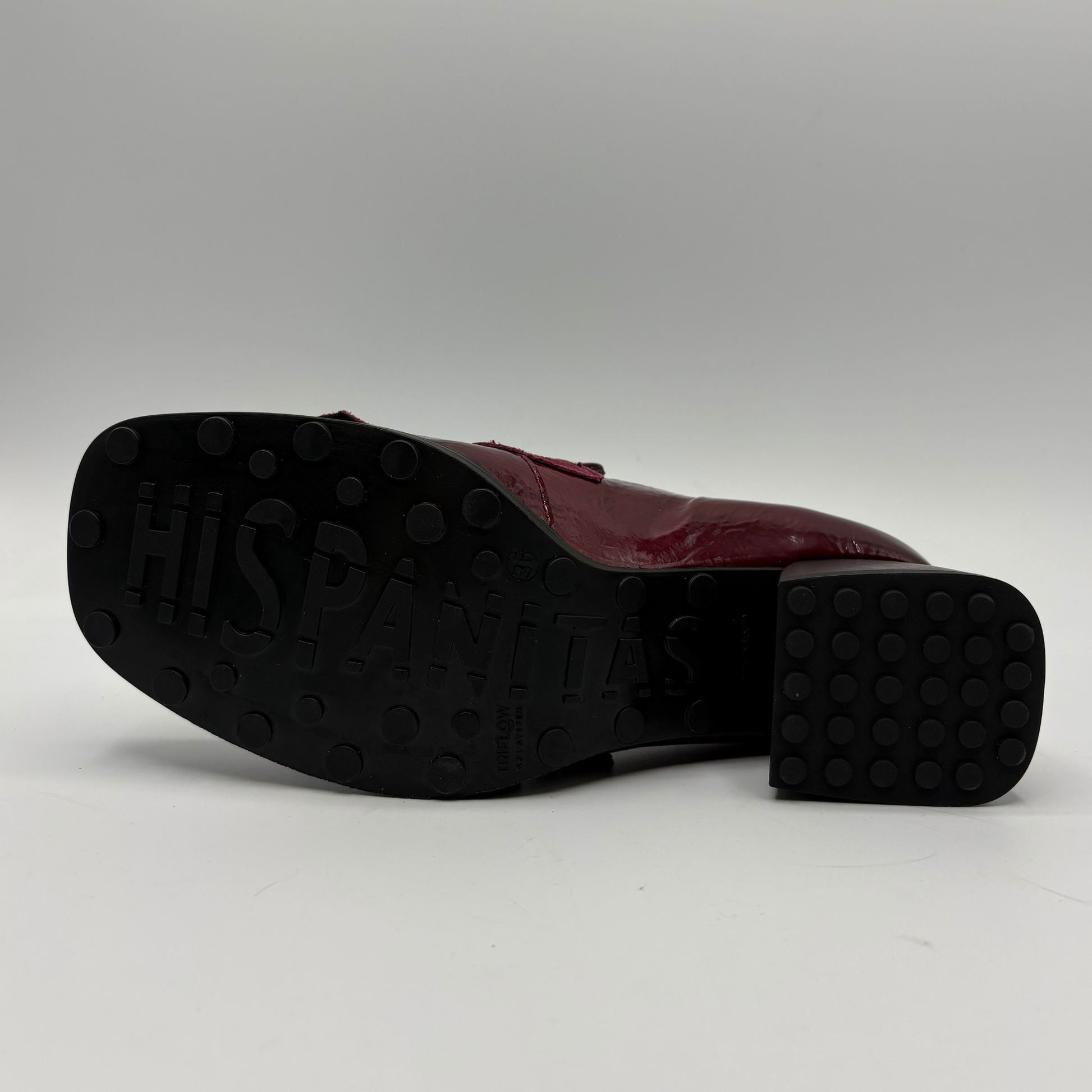 A single burgundy leather shoe shown from the side, with its black rubber outsole facing the camera. The outsole has 'HISPANITAS' embossed on it, indicating the brand.