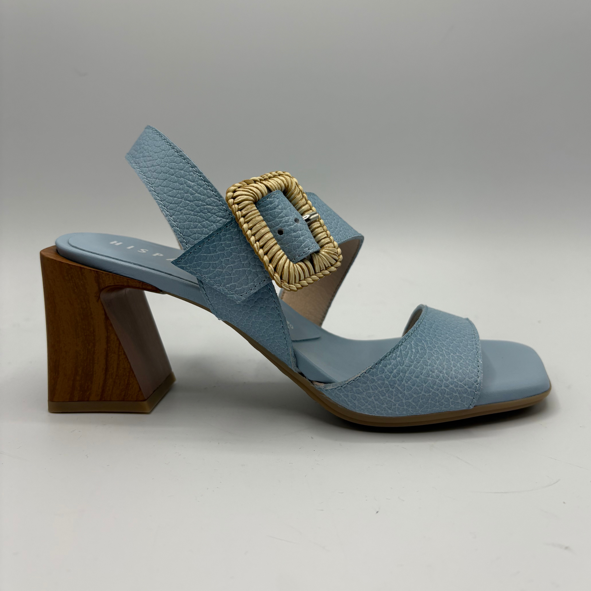 Blue sandal with a gold buckle on a gray background