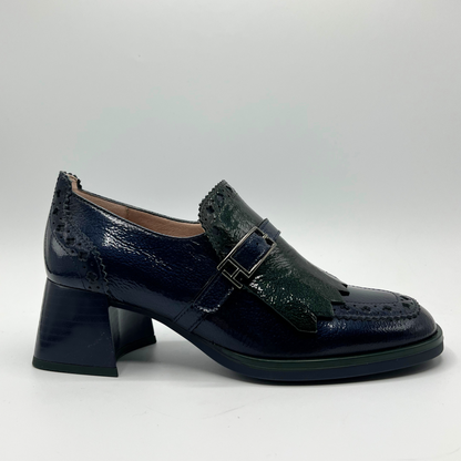 Navy blue leather shoe with a buckle on a light gray background