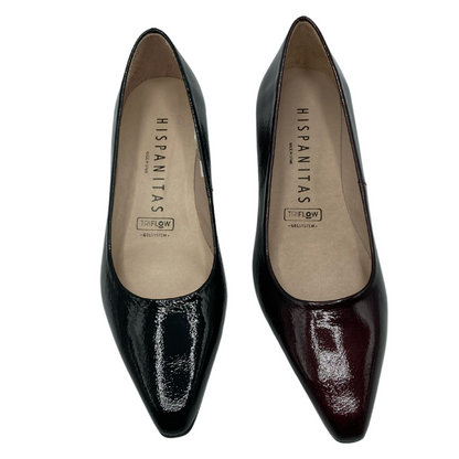 Top view of pair of patent leather pointy toe pumps, one black and one wine coloured