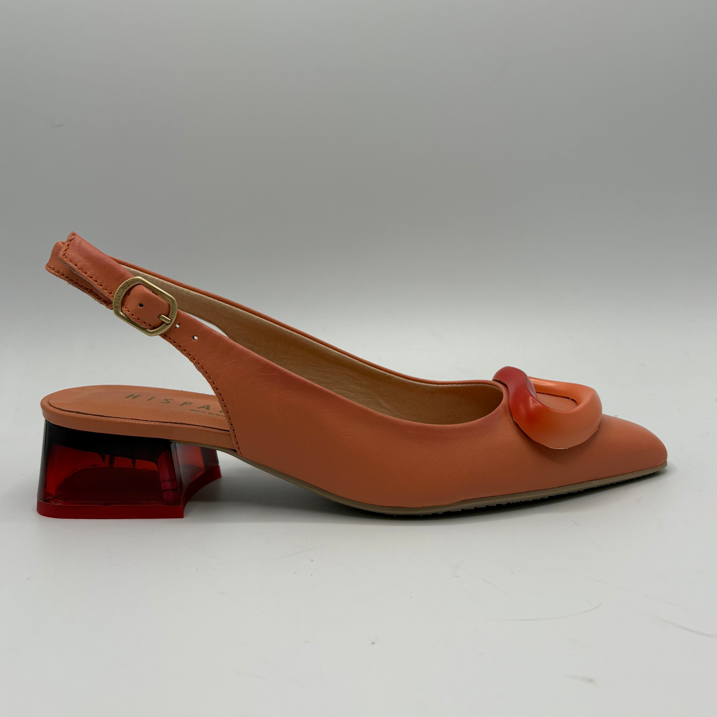Orange slingback shoe with a red buckle on a white background