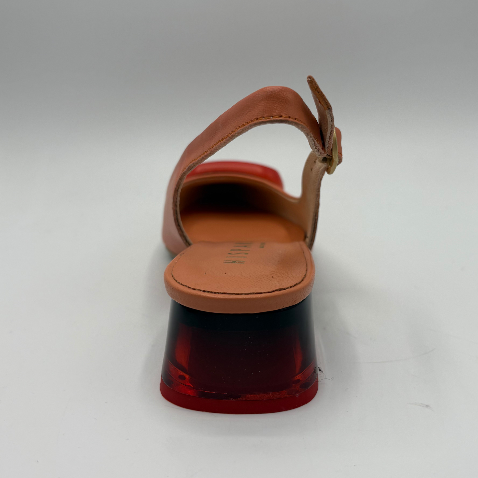 Orange sandal with a red sole on a white background