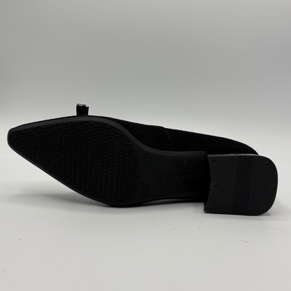 A black pointed-toe shoe shown from the sole side, featuring a textured rubber outsole and a block heel, photographed on a light gray background.