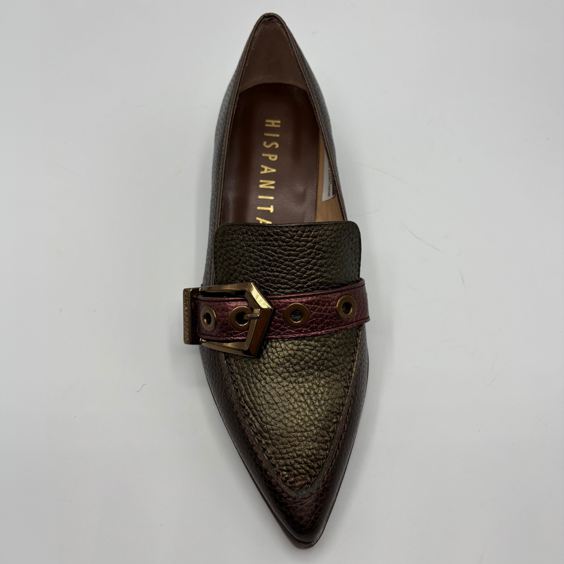 A single pointed-toe loafer in dark brown textured leather with a burgundy leather strap and gold-tone buckle, shown from a top-down view on a light gray background. The insole displays the brand name 'HISPANITAS'.