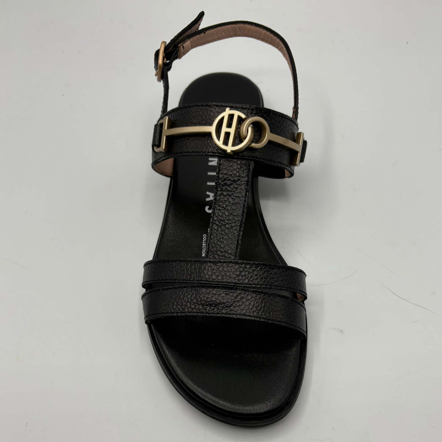 Black sandal with gold logo on a light gray background