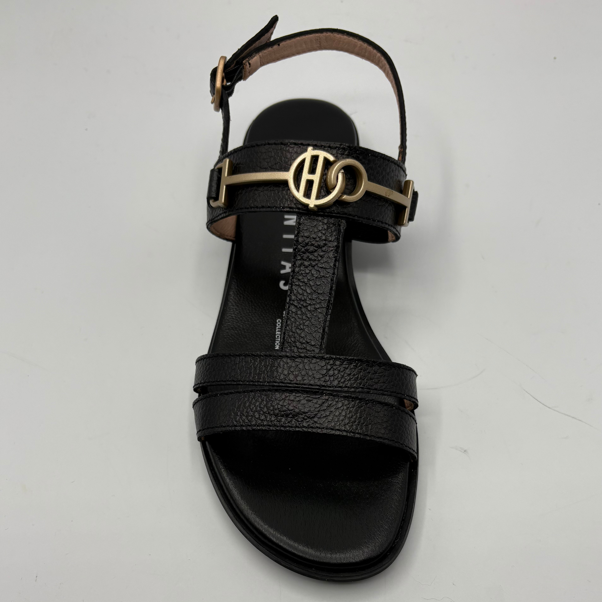 Black sandal with gold logo on a light gray background